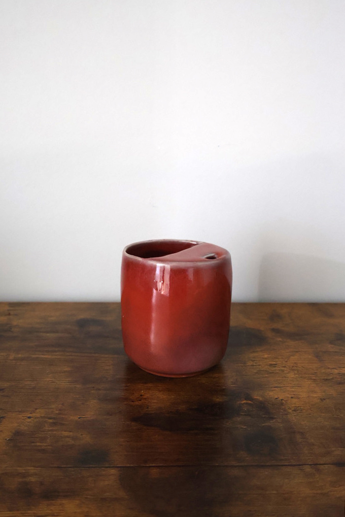 Deep red glazed ceramic cup with angled rim