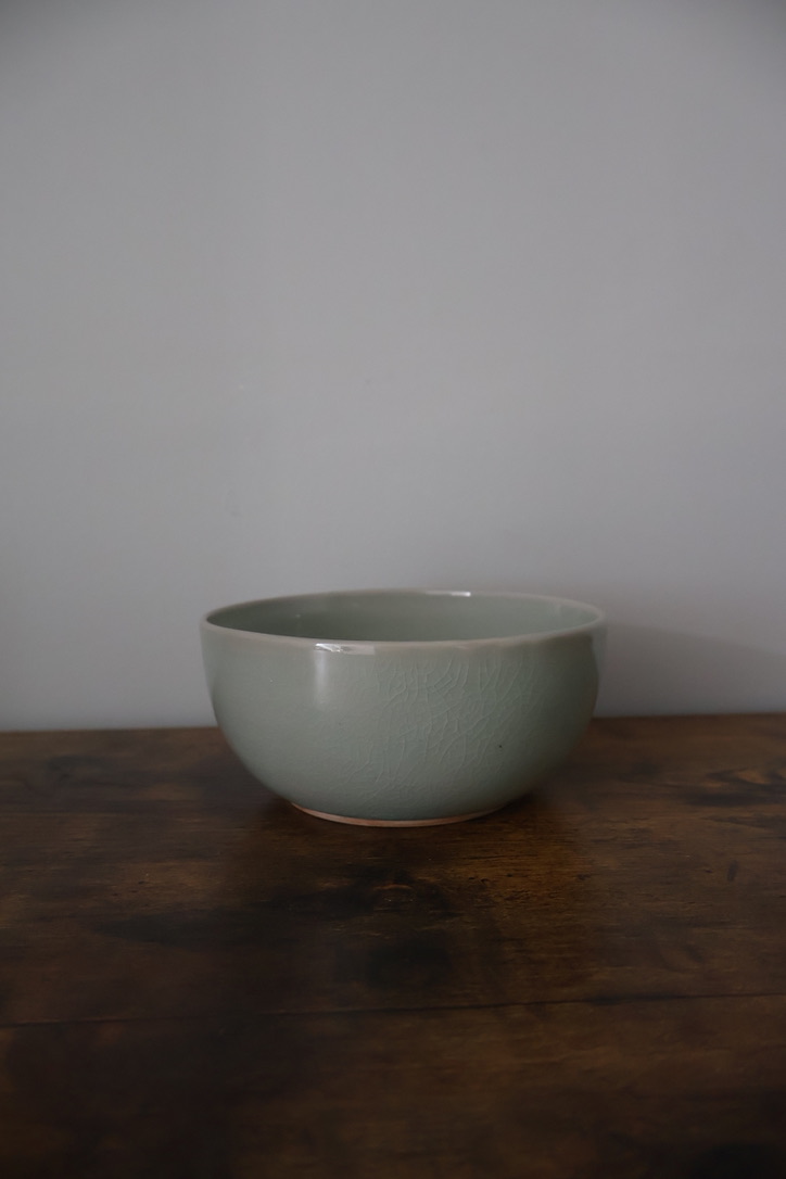 Celadon glazed stoneware bowl on a dark wooden table