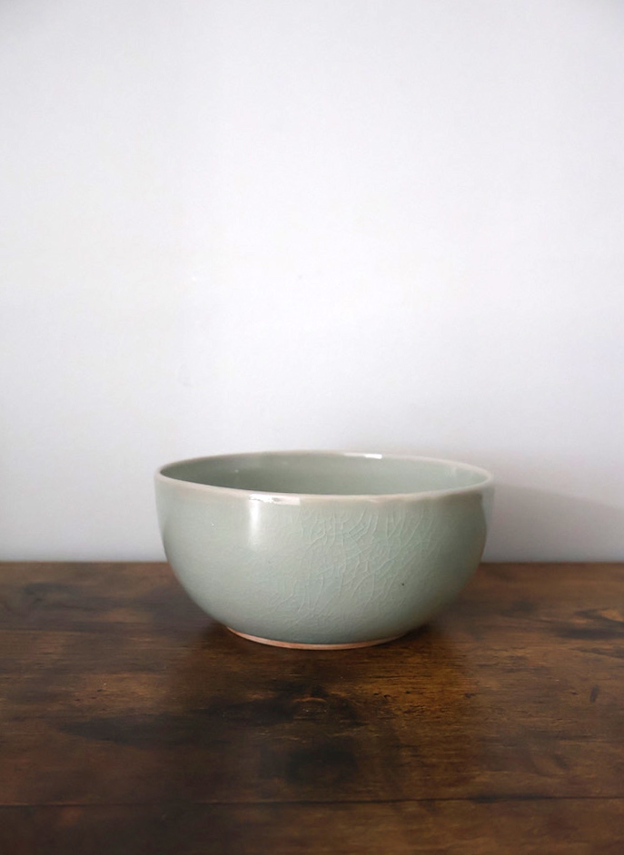Celadon glazed stoneware bowl on a dark wooden table